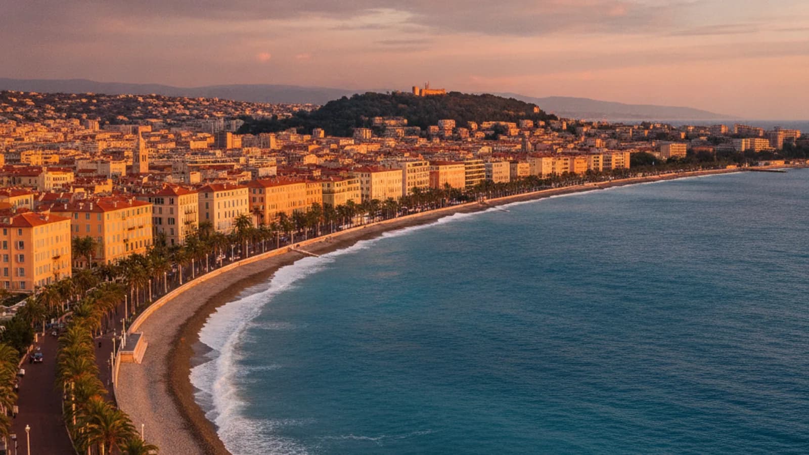 Vue panoramique de la Promenade des Anglais à Nice avec le soleil couchant sur la mer Méditerranée, des palmiers et des bâtiments historiques en arrière-plan.